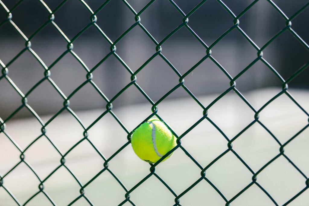 Photo by RDNE Stock project: https://www.pexels.com/photo/close-up-view-of-a-tennis-ball-on-a-wire-fence-8224406/